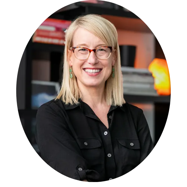Smiling therapist with blonde hair and glasses in a black shirt